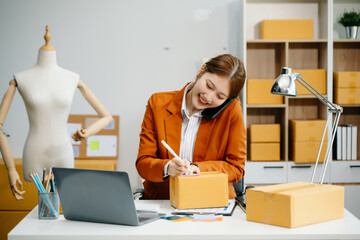 Young  woman prepare parcel box and standing check online orders for deliver to customer on tablet,...