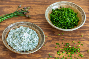 Homemade Greek Yogurt Chive dip in a clay bowl. A second bowl with chopped chives and chive stems...