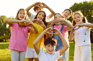 Portrait of a happy smiling children looking at the camera making heart shape gesture standing in...