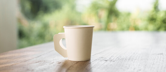 A paper coffee cup placed on a desk indoors, depicting a brief moment of pause or productivity. Workplace essentials, coffee break, and office culture converge.