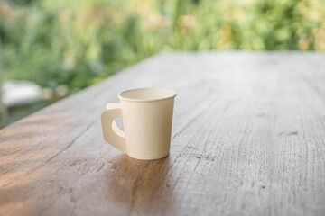 A paper coffee cup placed on a desk indoors, depicting a brief moment of pause or productivity. Workplace essentials, coffee break, and office culture converge.