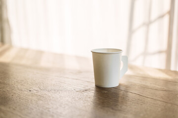 A paper coffee cup placed on a desk indoors, depicting a brief moment of pause or productivity....