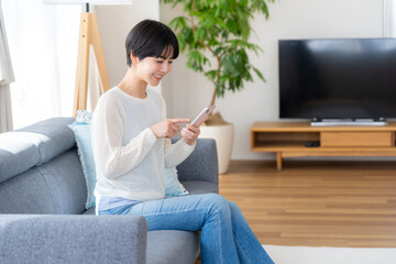 部屋でスマホを操作する女性