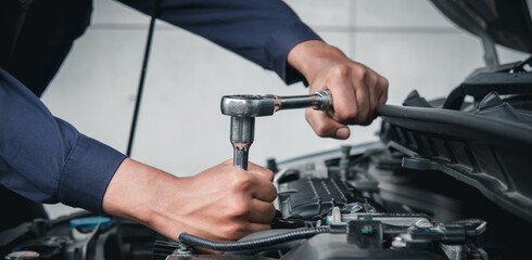 Mechanic using wrench while working on car engine outside the service center , Repair and service.