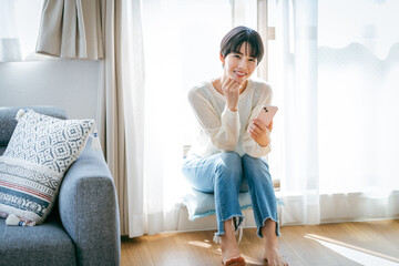 部屋でスマホを操作する女性