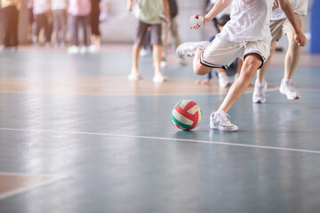Selective focus to futsal field floor with blurry ball and futsal player.  Futsal player playing ball.