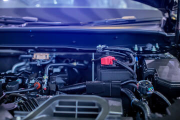 Selective focus to battery anode in the hybrid automotive car engine room. Red plus pole battery.