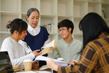 Mature female lecturer helping student during her class. Education, learning and knowledge concept