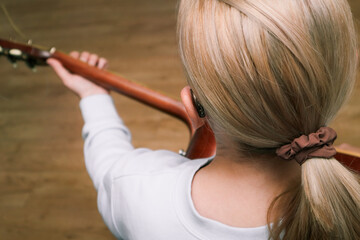 A woman with hearing loss can hear and play guitar again using a hearing aid. Adult woman with hearing aid behind the ear can hear sounds.