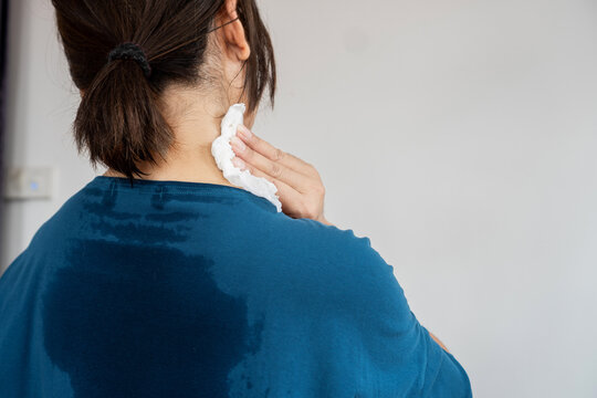 back view of sweating woman with wet cloth because of hot weather in summer time, menopause symptom concept