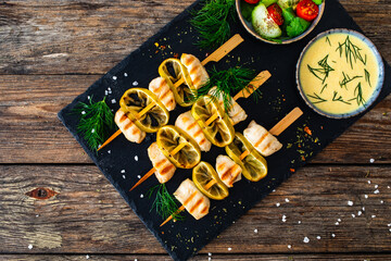 Poultry meat skewers - grilled meat with lime slices on wooden background
