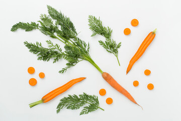 Flat lay with fresh carrots and leaves on white background, top view