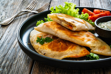 Cheburek - deep-fried turnovers filled with ground meat and vegetables on wooden table
