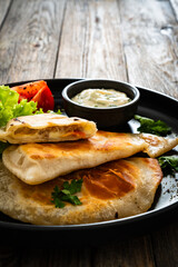 Cheburek - deep-fried turnovers filled with ground meat and vegetables on wooden table
