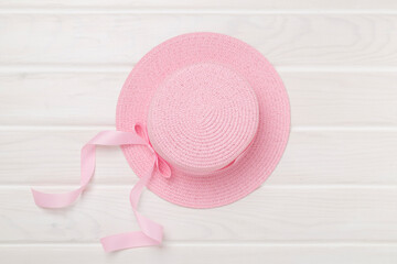 Pink hat on wooden background, top view. Summer concept
