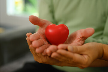 An elderly couple holding red heart symbol of love, health care, medical and charity concept