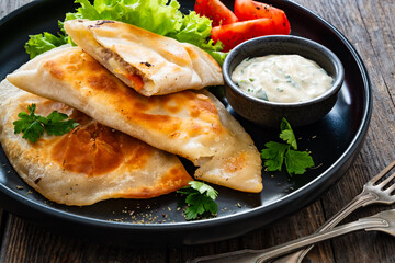 Cheburek - deep-fried turnovers filled with ground meat and vegetables on wooden table
