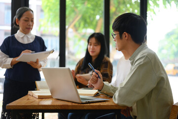 Young Asian student man using laptop while listening to lecture at the university
