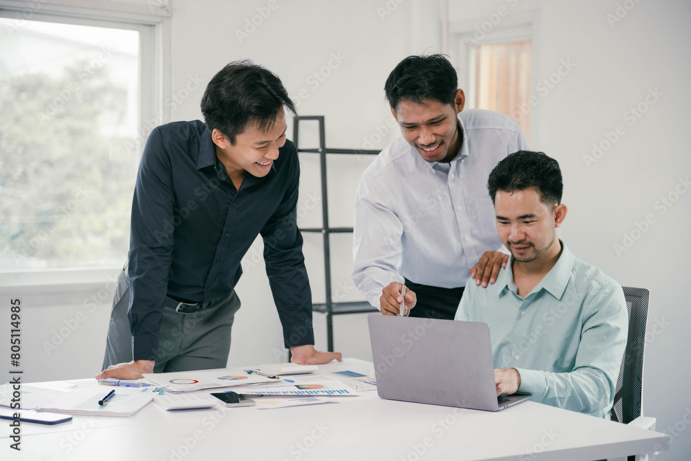 Poster Three men are sitting at a table with a laptop open in front of them