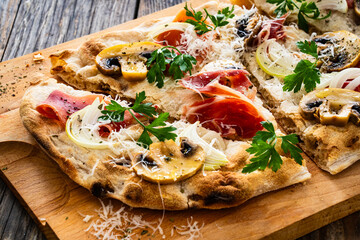 Roman Pinsa with mozzarella cheese, ripening ham and mushrooms on wooden table