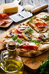 Roman Pinsa with mozzarella cheese, ripening ham and mushrooms on wooden table