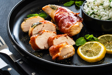 Chicken Saltimbocca - pan-fried chicken cutlets wrapped in Italian prosciutto slices on black...