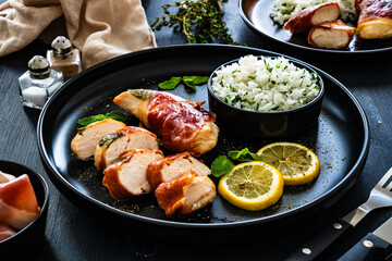 Chicken Saltimbocca - pan-fried chicken cutlets wrapped in Italian prosciutto slices on black...