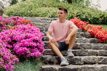 Handsome man sitting on the stairs in summer park.