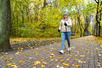 Mid-adult woman exercising Nordic walking in city park
