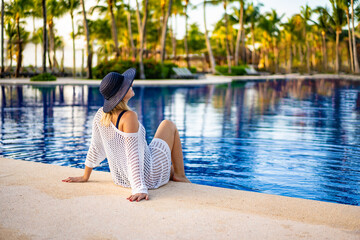 Woman relaxing sitting by resort pool
