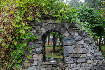 Old stone wall in the park. Wall with a small fountain for drinking water. Wall made of stone with...