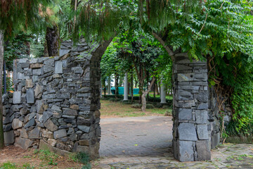 Old stone wall with an arch. Architectural idea, entrance to the forest.