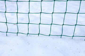 Green net in the snow. Close up on a soccer goal.