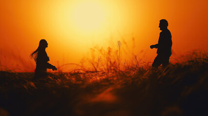 Silhouette of a couple in love against the background of a sunset in a field. Romantic scene of...