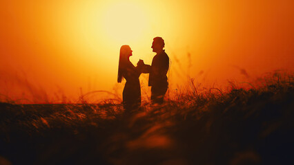 Sunset landscape with two lovers, a man and a woman. Beautiful nature in summer. Natural spikelets...