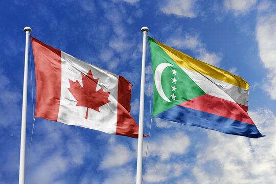 3D illustration. Canada and Comoros flags waving in the sky. High detailed waving flag. 3D render. Flags fluttered in the cloudy sky, symbolizing diplomatic relations.