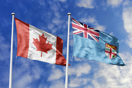 3D illustration. Canada and Fiji flags waving in the sky. High detailed waving flag. 3D render. Flags fluttered in the cloudy sky, symbolizing diplomatic relations.