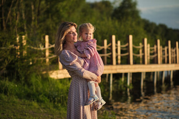 Woman with child in the golden hour light, nature around. Speaks to hope, reflection, and the bond...