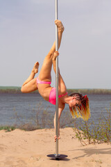 A skinny pole dance girl show her extrimelly skills with pole outdoor on islands