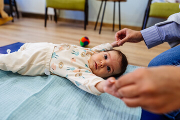 Adorable baby enjoys physical therapy sessions with a qualified therapist in a specialized children's gym or play area.