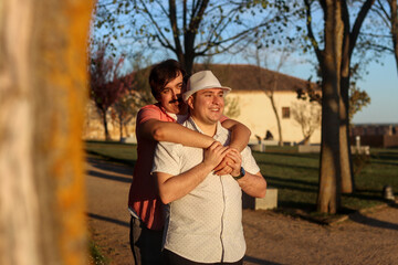 Couple of gay smiling men hugging standing with the light of the sunset giving them in a park, normal people. LGBT love concept