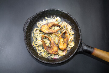Ilish bhaji for Panta ilish, Bengali new year festive dish. Fried Hilsha slices with chilli and onion. Ilsha fry on black pan. Hilsa fry is popular in pohela boishakh.