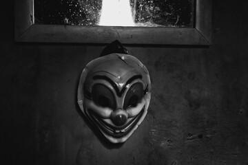 a clown mask hanging on the wall of a dark room