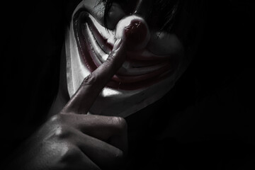 Creepy clown in the dark, horror concept wearing a clown mask