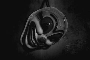 a clown mask hanging on the wall of a dark room