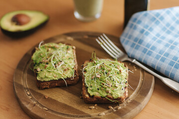 Healthy vegan breakfast. Guacamole toasted bread with microgreen and sunflower seeds. Green smoothie