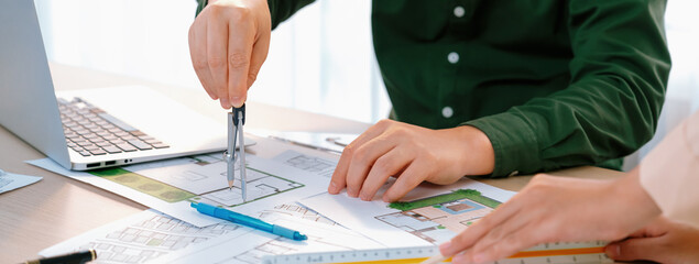 A cropped image of professional engineer using divider to measure blueprint at meeting table with...