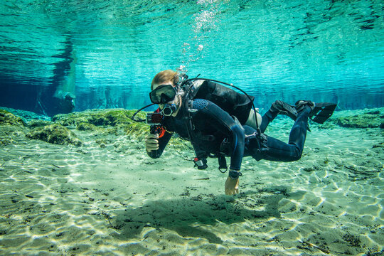 Diver swimming underwater holding a camera, Three Sisters Springs, Crystal River, Florida, USA