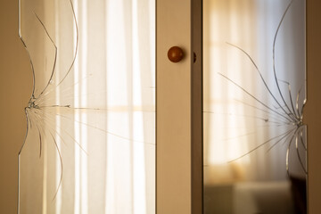 Broken mirrors on the wardrobe door. Reflection of the window and tulle curtain in the mirror. Male...