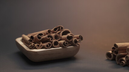 Cinnamon sticks on a wooden plate in the dark background